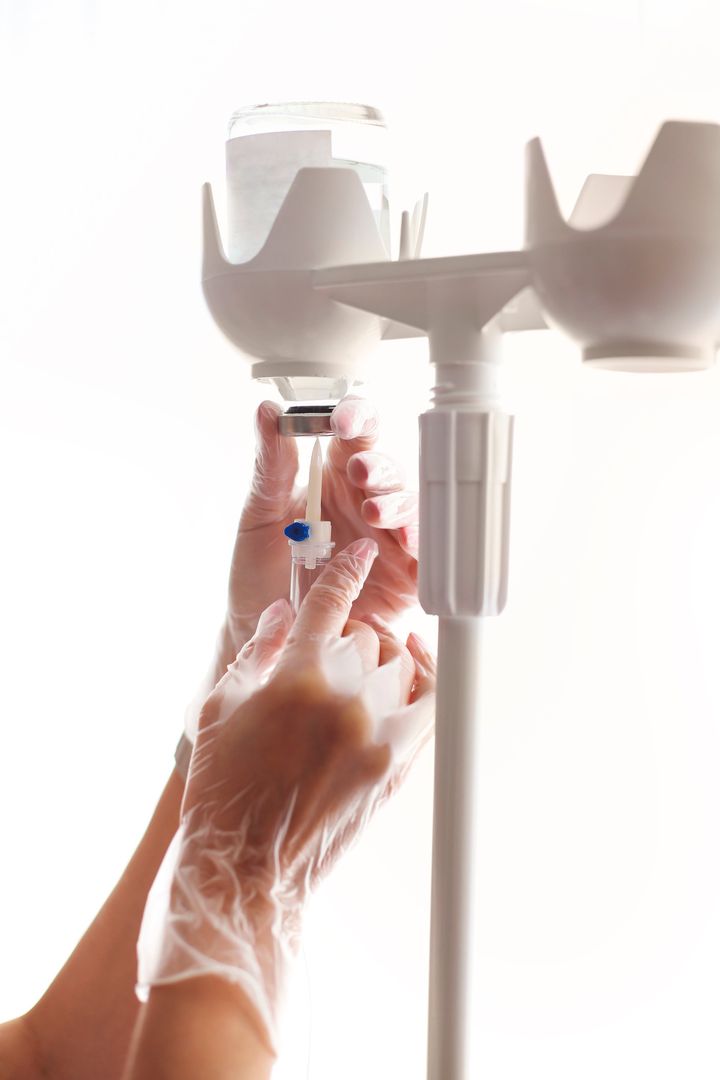 Manos con guantes preparando un equipo de infusión, dispositivo médico