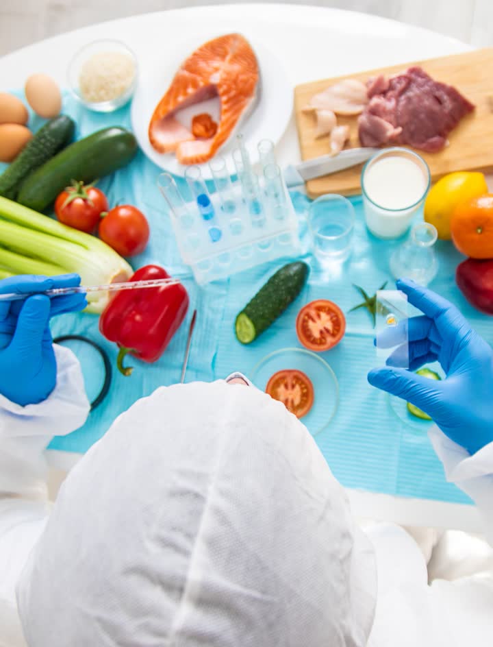 Alimentos frescos y manos con guantes sobre una mesa, control de inocuidad alimentaria